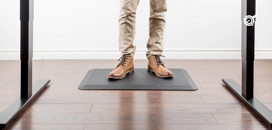 A man on a standing desk mat with oxford shoes